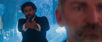 Movie still from “Mission: Impossible - Dead Reckoning Part One” (2023), directed by Christopher McQuarrie – A man in a suit holding a gun in front of another man in a suit; Medium shot, Over the shoulder angle