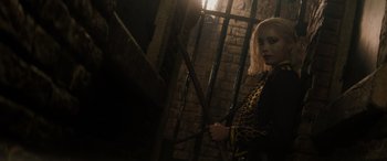 Movie still from “Mission: Impossible - Dead Reckoning Part One” (2023), directed by Christopher McQuarrie – A woman holding a cane standing next to a brick wall; Medium shot, High angle