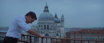 Movie still from “Mission: Impossible - Dead Reckoning Part One” (2023), directed by Christopher McQuarrie – A man standing on top of a balcony looking at a building; Medium shot, Low angle