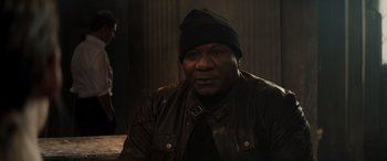 Movie still from “Mission: Impossible - Dead Reckoning Part One” (2023), directed by Christopher McQuarrie – A man wearing a leather jacket and a black hat; Medium shot, Over the shoulder angle