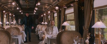Movie still from “Mission: Impossible - Dead Reckoning Part One” (2023), directed by Christopher McQuarrie – A woman sitting at a table in a train car; Wide shot, Over the shoulder angle