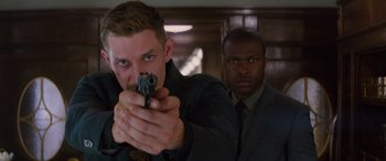 Movie still from “Mission: Impossible - Dead Reckoning Part One” (2023), directed by Christopher McQuarrie – A man holding a gun in front of another man in a suit; Close Up shot, Over the shoulder angle