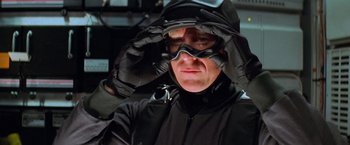 Movie still from “Mission: Impossible II” (2000), directed by John Woo – A man in a black suit with a mask on his head; Close Up shot, Low angle