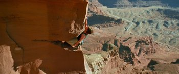 Movie still from “Mission: Impossible II” (2000), directed by John Woo – A man climbing a rock wall in the desert; Wide shot, Overhead angle