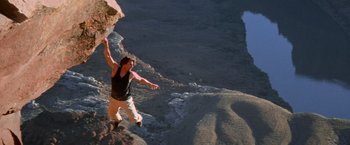 Movie still from “Mission: Impossible II” (2000), directed by John Woo – A man standing on top of a rock cliff; Wide shot, High angle