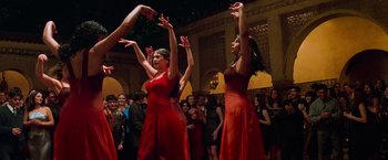 Movie still from “Mission: Impossible II” (2000), directed by John Woo – A group of women in red dresses dancing in front of a crowd; Wide shot, Low angle
