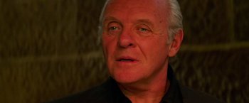 Movie still from “Mission: Impossible II” (2000), directed by John Woo – An older man with a goatee looking at the camera; Close Up shot, Over the shoulder angle