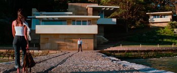 Movie still from “Mission: Impossible II” (2000), directed by John Woo – A man standing in front of a building on a gravel road; Extreme Wide shot, Low angle