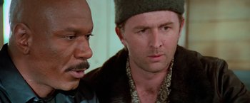 Movie still from “Mission: Impossible II” (2000), directed by John Woo – A man in a hat is talking to another man in a black jacket; Close Up shot, Low angle