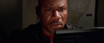 Movie still from “Mission: Impossible II” (2000), directed by John Woo – A man with headphones looking at a camera; Close Up shot, High angle