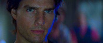 Movie still from “Mission: Impossible II” (2000), directed by John Woo – A man's face with blue light shining on it; Close Up shot, Over the shoulder angle