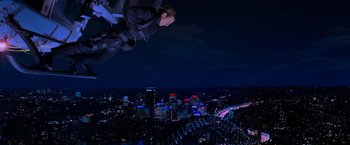 Movie still from “Mission: Impossible II” (2000), directed by John Woo – A man flying through the air over a city at night; Wide shot, High angle