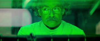 Movie still from “Mission: Impossible II” (2000), directed by John Woo – A man with a beard and mustache wearing glasses and a white shirt; Close Up shot, Low angle