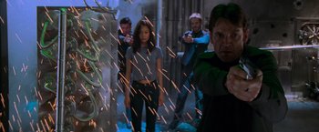 Movie still from “Mission: Impossible II” (2000), directed by John Woo – A group of people standing in a room holding guns; Medium shot, Low angle