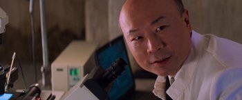 Movie still from “Mission: Impossible II” (2000), directed by John Woo – A person with a microscope; Close Up shot, Low angle