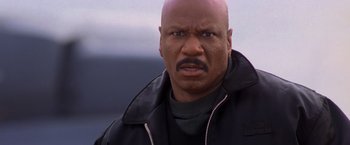 Movie still from “Mission: Impossible II” (2000), directed by John Woo – A man with a bald head wearing a black jacket; Close Up shot, Low angle