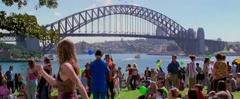 Movie still from “Mission: Impossible II” (2000), directed by John Woo – A group of people standing on top of a grass covered field; Extreme Wide shot, High angle