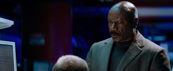 Movie still from “Mission: Impossible III” (2006), directed by J.J. Abrams – An older man in a gray suit talking to a younger man; Close Up shot, Over the shoulder angle
