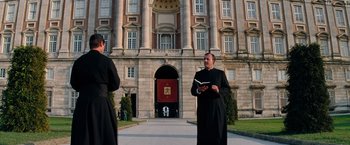 Movie still from “Mission: Impossible III” (2006), directed by J.J. Abrams – Two men dressed in black standing in front of a building; Wide shot, Low angle
