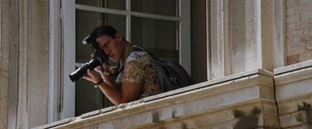 Movie still from “Mission: Impossible III” (2006), directed by J.J. Abrams – A man with a backpack taking a picture from a window; Medium shot, Low angle
