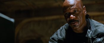 Movie still from “Mission: Impossible III” (2006), directed by J.J. Abrams – A man with a beard and mustache is looking at the camera; Close Up shot, Low angle