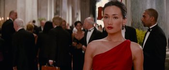 Movie still from “Mission: Impossible III” (2006), directed by J.J. Abrams – A woman in a red dress standing next to other people; Close Up shot, Over the shoulder angle