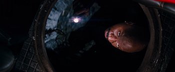 A man is looking up at a flashlight in the dark
