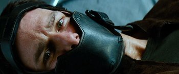 Movie still from “Mission: Impossible III” (2006), directed by J.J. Abrams – A man wearing a black leather muzzle with his mouth wide open; Close Up shot, Overhead angle