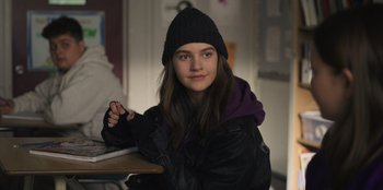 Movie still from “Mixtape” (2021), directed by Valerie Weiss – A young woman sitting at a table in a room; Close Up shot, High angle