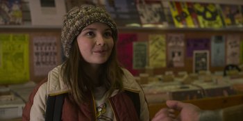 Movie still from “Mixtape” (2021), directed by Valerie Weiss – A young woman wearing a hat and a jacket; Close Up shot, Over the shoulder angle