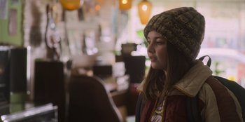 Movie still from “Mixtape” (2021), directed by Valerie Weiss – A young girl wearing a hat and a jacket; Close Up shot, Over the shoulder angle