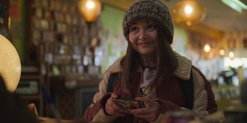 Movie still from “Mixtape” (2021), directed by Valerie Weiss – A young girl holding a cell phone in her hands; Medium shot, Over the shoulder angle