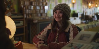 Movie still from “Mixtape” (2021), directed by Valerie Weiss – A young girl smiles as she holds a cell phone; Close Up shot, Over the shoulder angle
