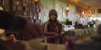 Movie still from “Mixtape” (2021), directed by Valerie Weiss – A woman standing in front of a bunch of records; Medium shot, Over the shoulder angle