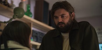 Movie still from “Mixtape” (2021), directed by Valerie Weiss – A man with a beard is looking at a woman; Medium shot, Over the shoulder angle