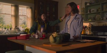 Movie still from “Mixtape” (2021), directed by Valerie Weiss – Two people sitting at a table in a room; Medium shot, Over the shoulder angle