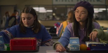 Movie still from “Mixtape” (2021), directed by Valerie Weiss – Two young girls sitting at a table in a cafeteria; Medium shot, Over the shoulder angle