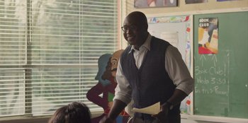 Movie still from “Mixtape” (2021), directed by Valerie Weiss – An older man in a vest and tie holding a paper; Medium shot, Over the shoulder angle