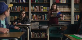 Movie still from “Mixtape” (2021), directed by Valerie Weiss – Two young girls are reading books in a library; Medium shot, Over the shoulder angle
