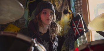 Movie still from “Mixtape” (2021), directed by Valerie Weiss – A girl in a beanie and jacket looking at the camera; Close Up shot, Over the shoulder angle