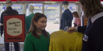 Movie still from “Mixtape” (2021), directed by Valerie Weiss – A young girl is looking at a yellow sweater; Medium shot, Over the shoulder angle