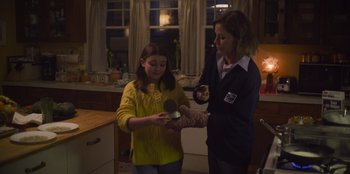 Movie still from “Mixtape” (2021), directed by Valerie Weiss – A woman and a young girl are holding a microphone; Medium shot, Over the shoulder angle