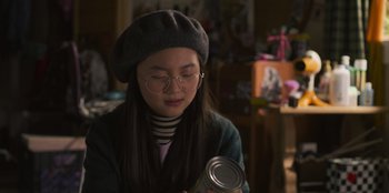 Movie still from “Mixtape” (2021), directed by Valerie Weiss – A woman wearing a hat and glasses holding a can of food; Close Up shot, Over the shoulder angle