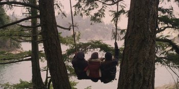 Movie still from “Mixtape” (2021), directed by Valerie Weiss – A group of people hanging from a tree swing; Extreme Wide shot, High angle