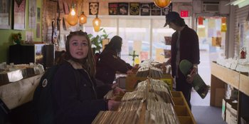 Movie still from “Mixtape” (2021), directed by Valerie Weiss – A woman is looking at records at a record store; Medium shot, Over the shoulder angle