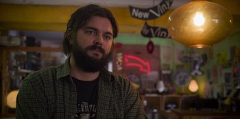Movie still from “Mixtape” (2021), directed by Valerie Weiss – A man with long hair and a goatee stares into the camera; Close Up shot, Low angle