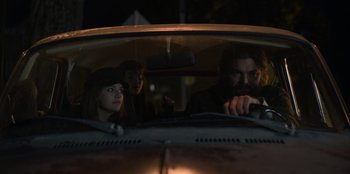 Movie still from “Mixtape” (2021), directed by Valerie Weiss – A group of people in the back of a car at night; Medium shot, Low angle