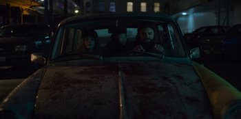 Movie still from “Mixtape” (2021), directed by Valerie Weiss – A group of people sitting in the back of an old car; Medium shot, Low angle
