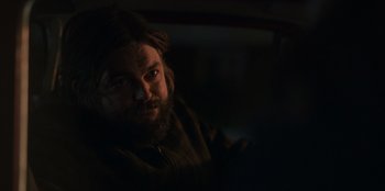Movie still from “Mixtape” (2021), directed by Valerie Weiss – A bearded man sitting in the back seat of a car; Close Up shot, Over the shoulder angle