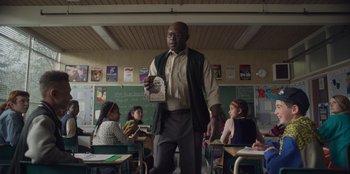 Movie still from “Mixtape” (2021), directed by Valerie Weiss – A man standing in front of a group of children; Medium shot, Low angle